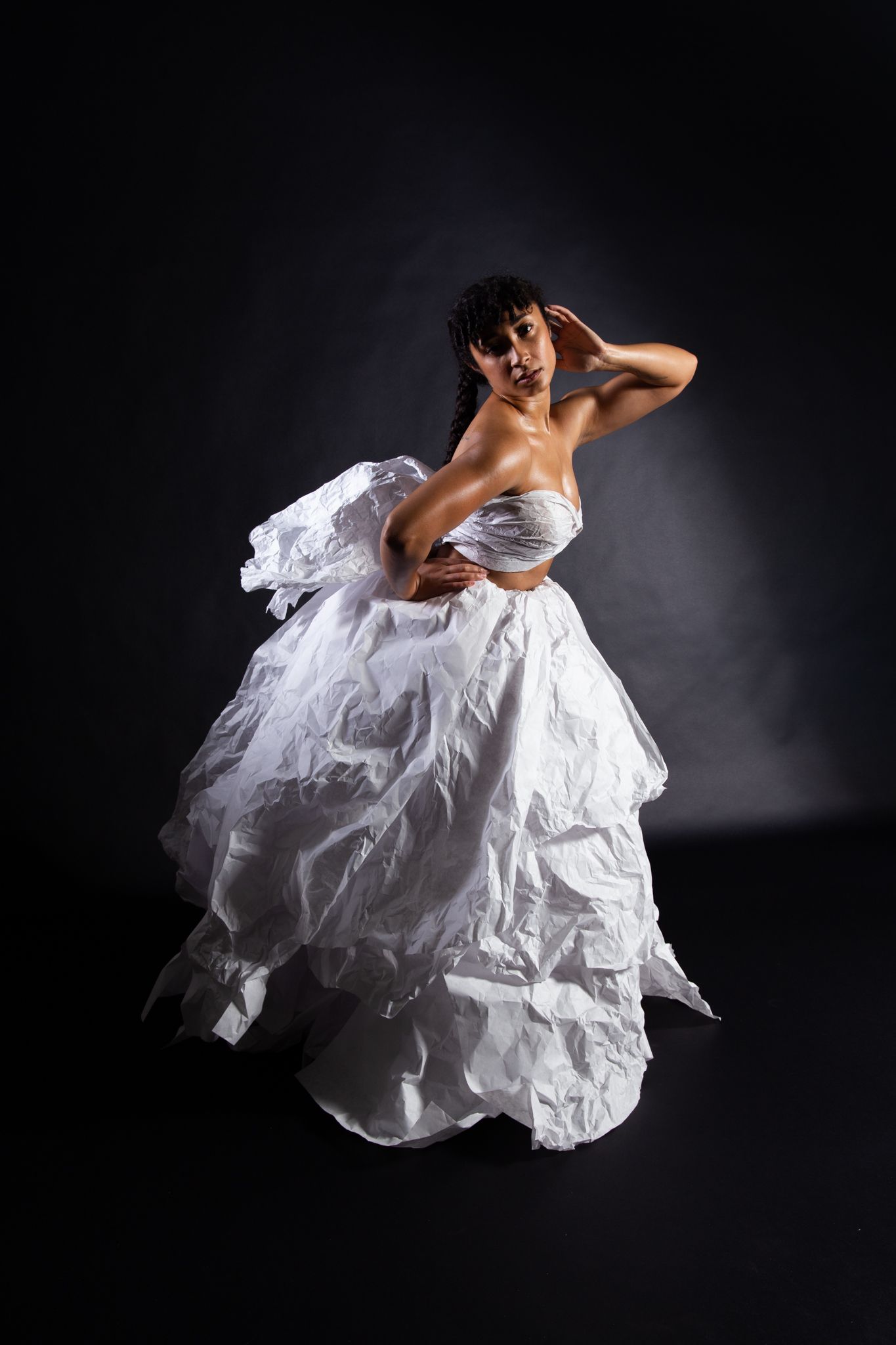 Woman in white strapless dress, dark studio setting. Posing with hand on head, dramatic lighting; art by Matt Remsbecher. 