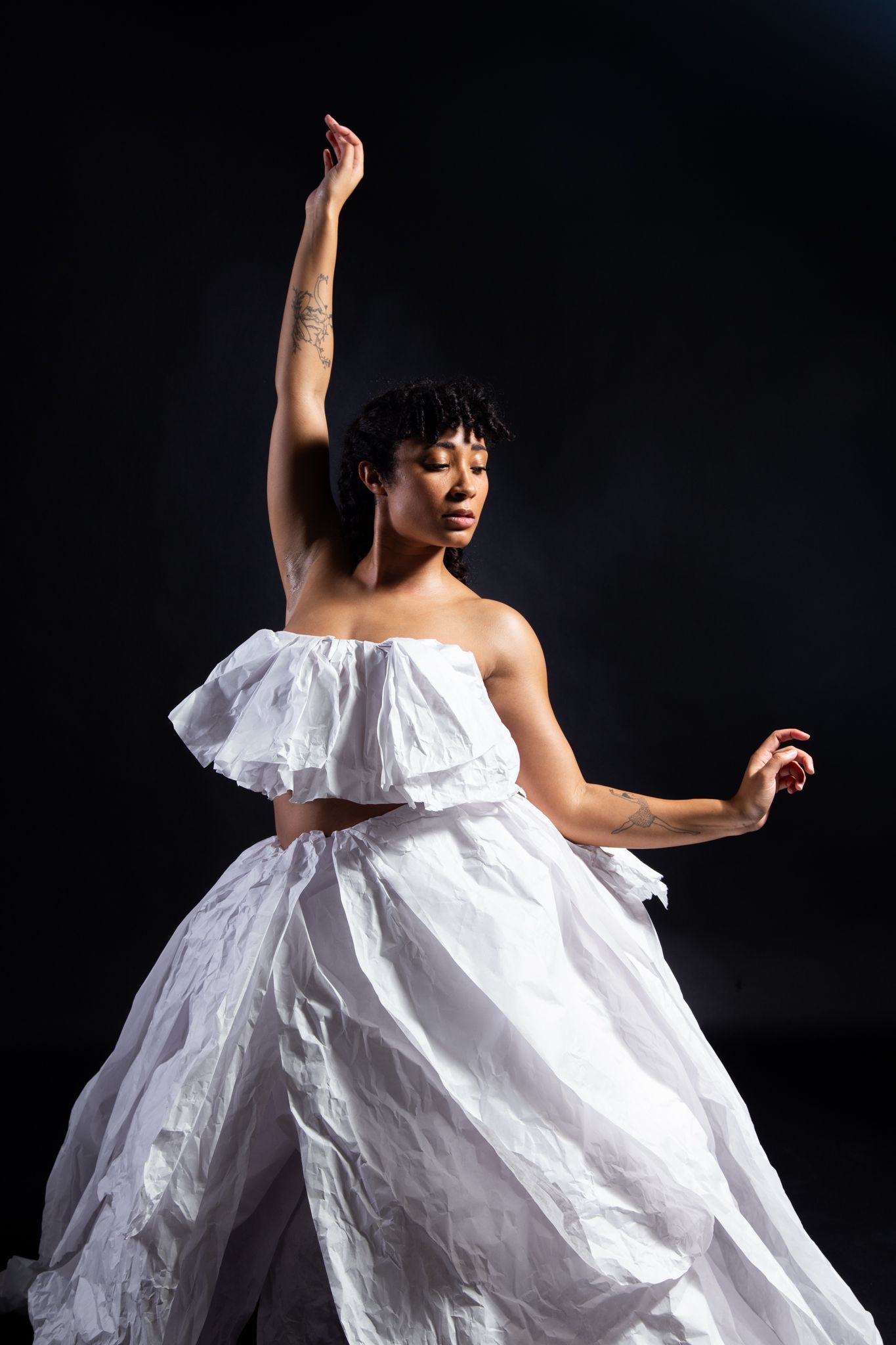 Woman in white, layered outfit, arm raised, dark background; art by Matt Remsbecher. 