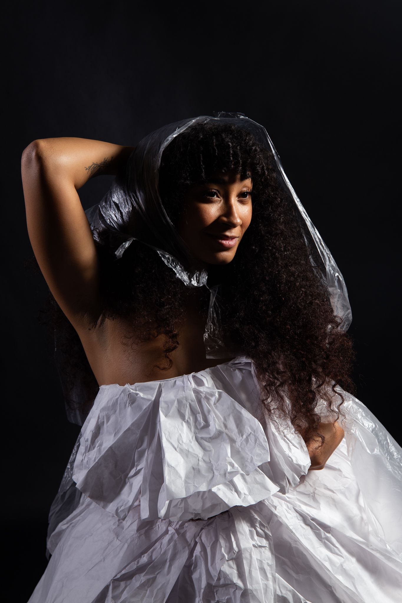 Woman with long curly hair, wearing a white, textured garment and veil, against a black background; art by Matt Remsbecher. 