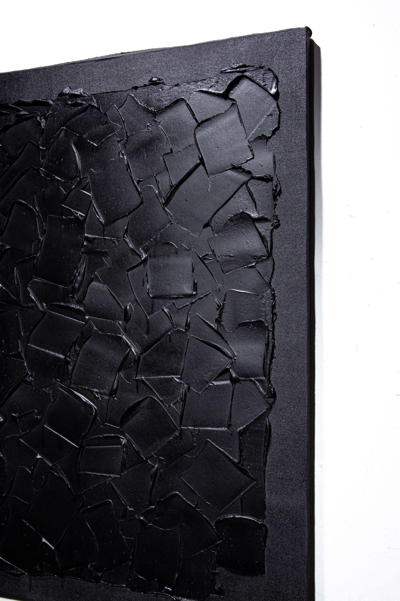 Black textured abstract art piece with a dark border on a white wall; art by Matt Remsbecher. 