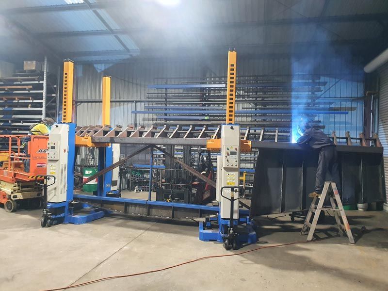 A man is welding a large piece of metal in a factory.