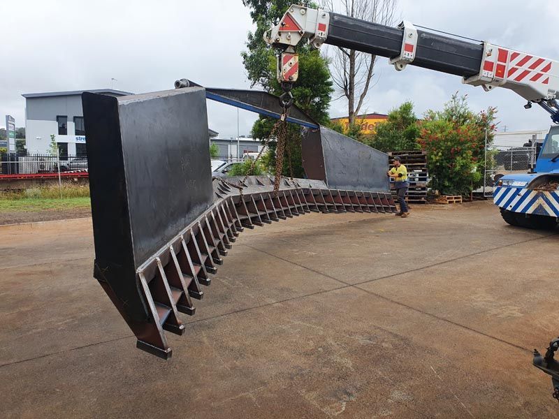 A large piece of metal is being lifted by a crane.