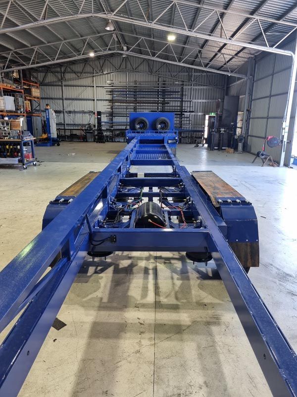 A blue trailer is sitting in a large warehouse.