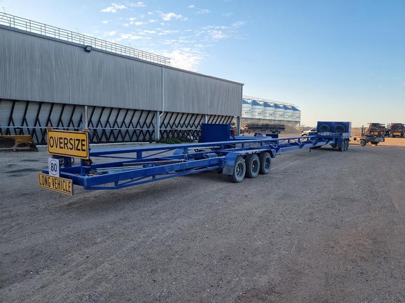 A blue trailer is parked in front of a building.