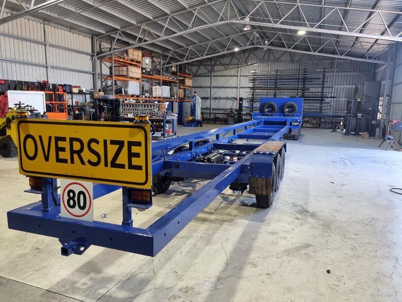 A blue trailer with a yellow sign that says `` oversize '' is in a warehouse.