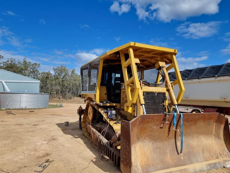 A yellow bulldozer is parked in a dirt field.