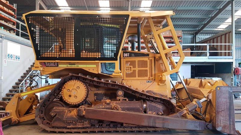 A yellow bulldozer is parked in a warehouse.
