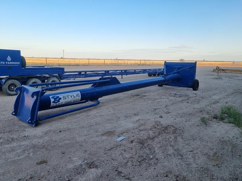 A large blue pipe is sitting in the middle of a dirt field.