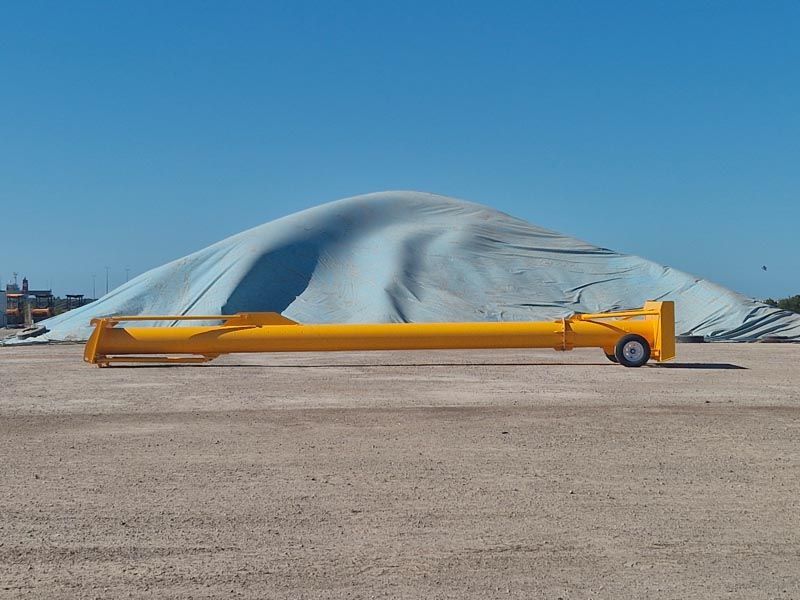 A yellow pole is sitting in front of a large pile of sand