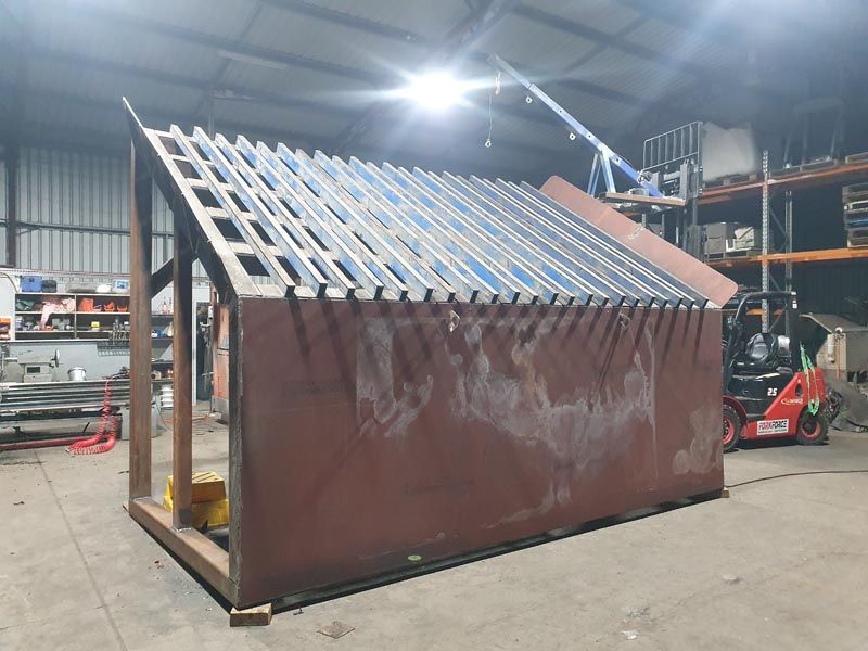 A shed is being built in a warehouse with a forklift in the background.