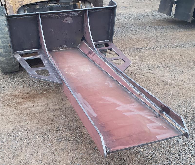 A metal ramp is attached to the back of a tractor