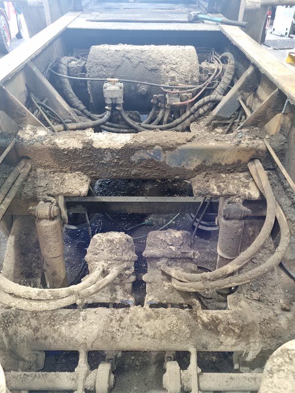 The underside of a dirty truck with a lot of wires coming out of it.
