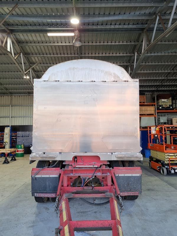 A large aluminum trailer is parked in a warehouse.