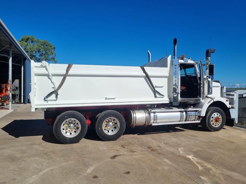 A white dump truck is parked in a parking lot.