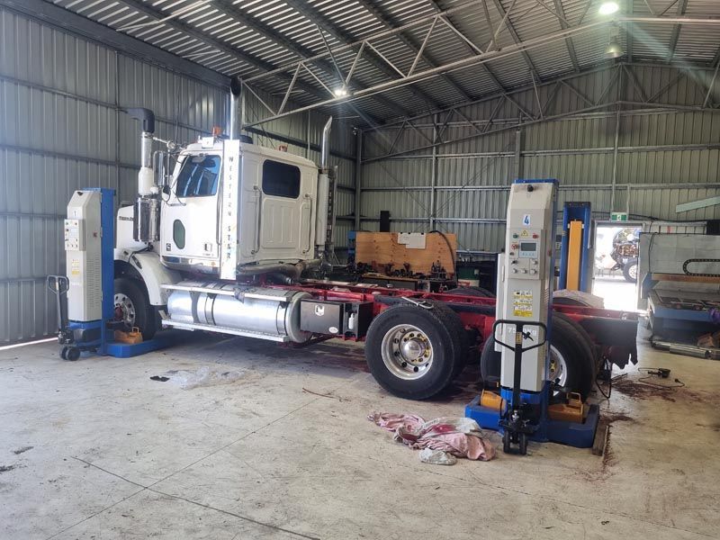 A semi truck is sitting on a lift in a garage.