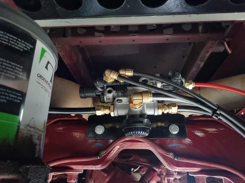 A bucket of gear oil sits next to a hydraulic valve