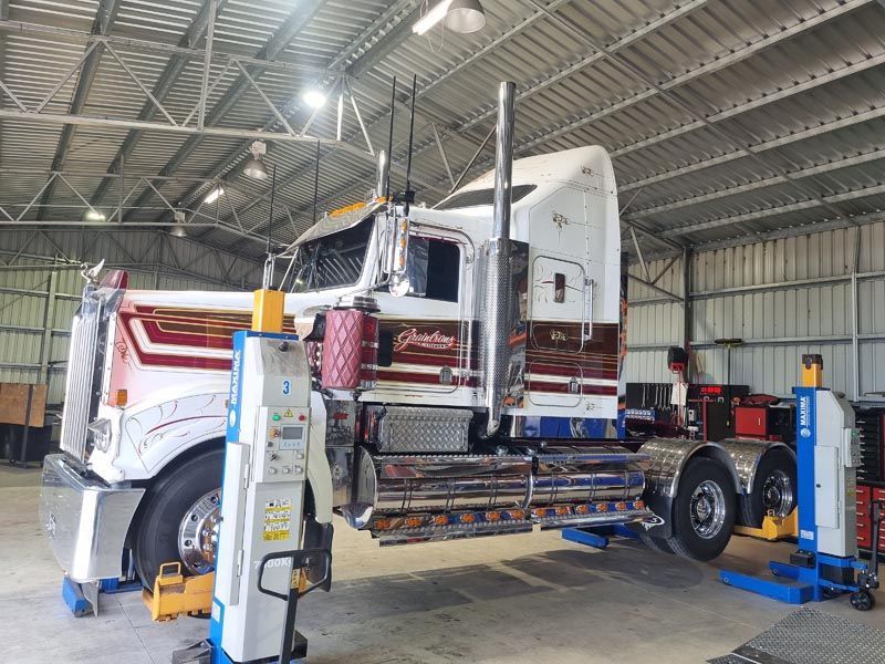 A semi truck is sitting on a lift in a garage.