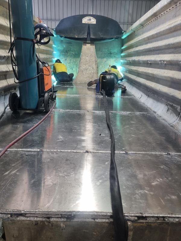 Two men are welding a metal structure in a factory.