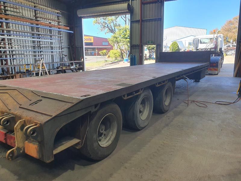 A flatbed trailer is parked in a garage.
