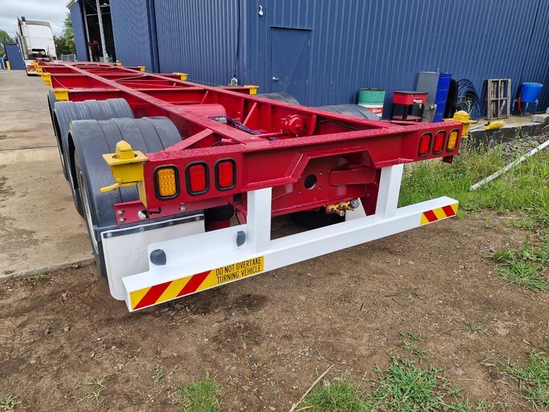 A red trailer is parked in front of a blue building.