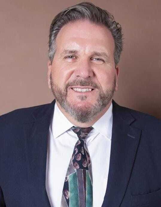 A man in a suit and tie is smiling for the camera.