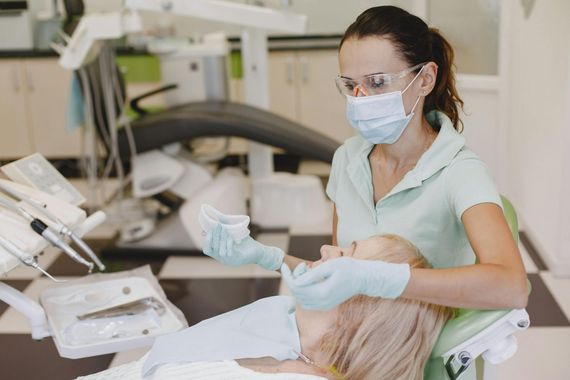 A female dentist is examining a patient 's teeth in a dental office.