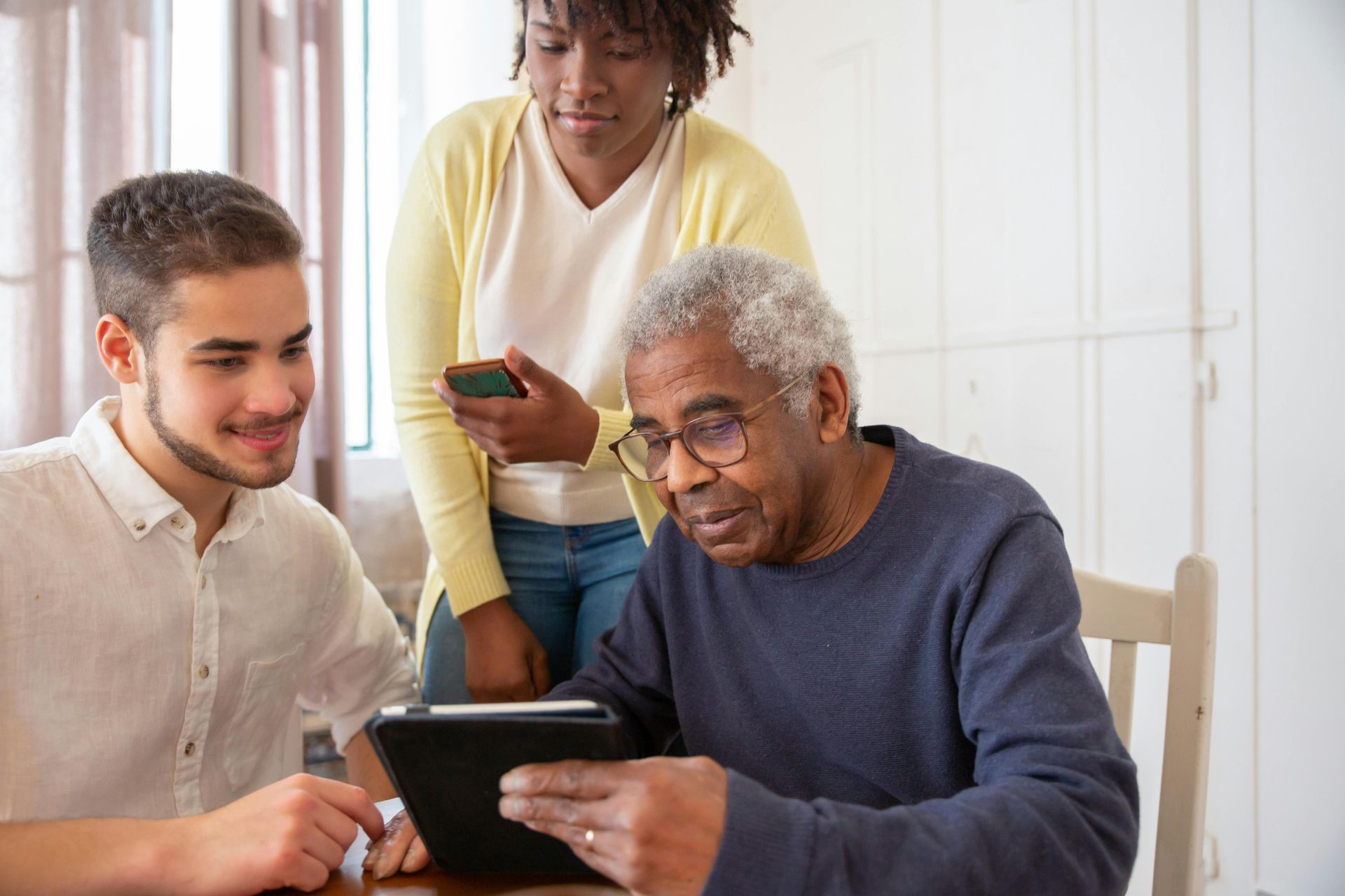 A group of people are sitting at a table looking at a tablet.