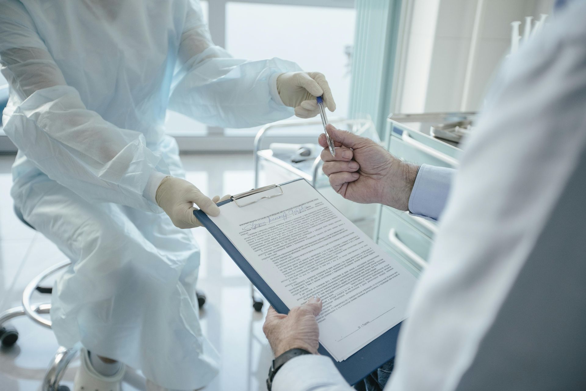 A doctor is giving a patient a pen and a clipboard in a hospital.