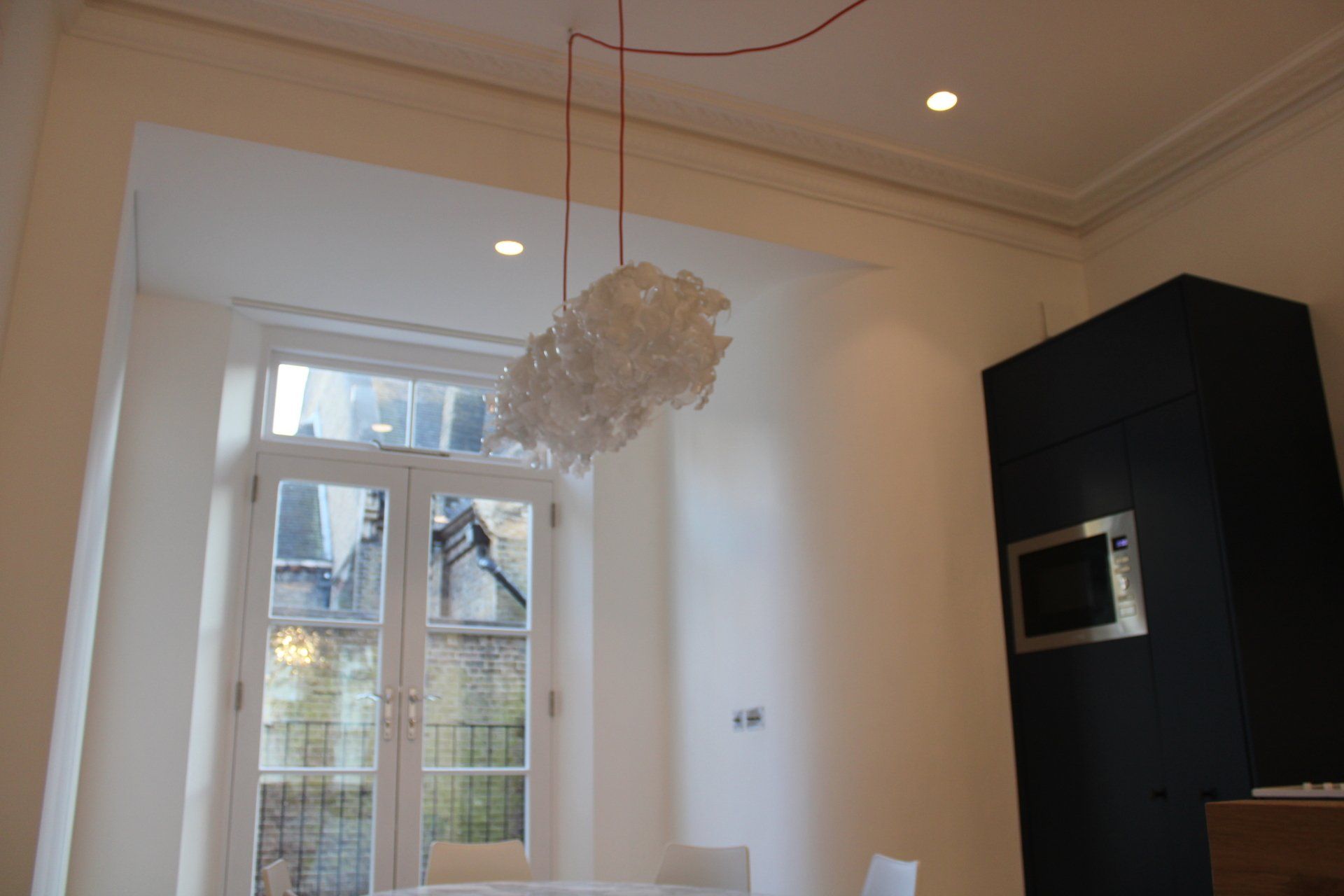 Interior with white walls, window, and modern chandelier; black oven casing.