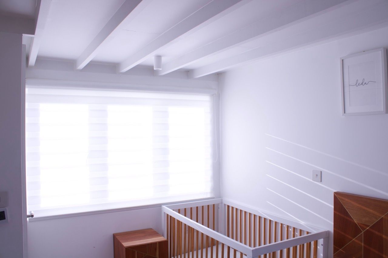 White nursery with crib, window, and decorative ceiling beams.