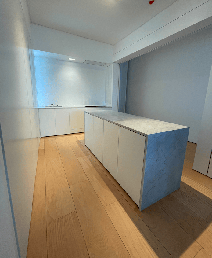 Kitchen with white cabinets, light wood floor, and a gray countertop island.
