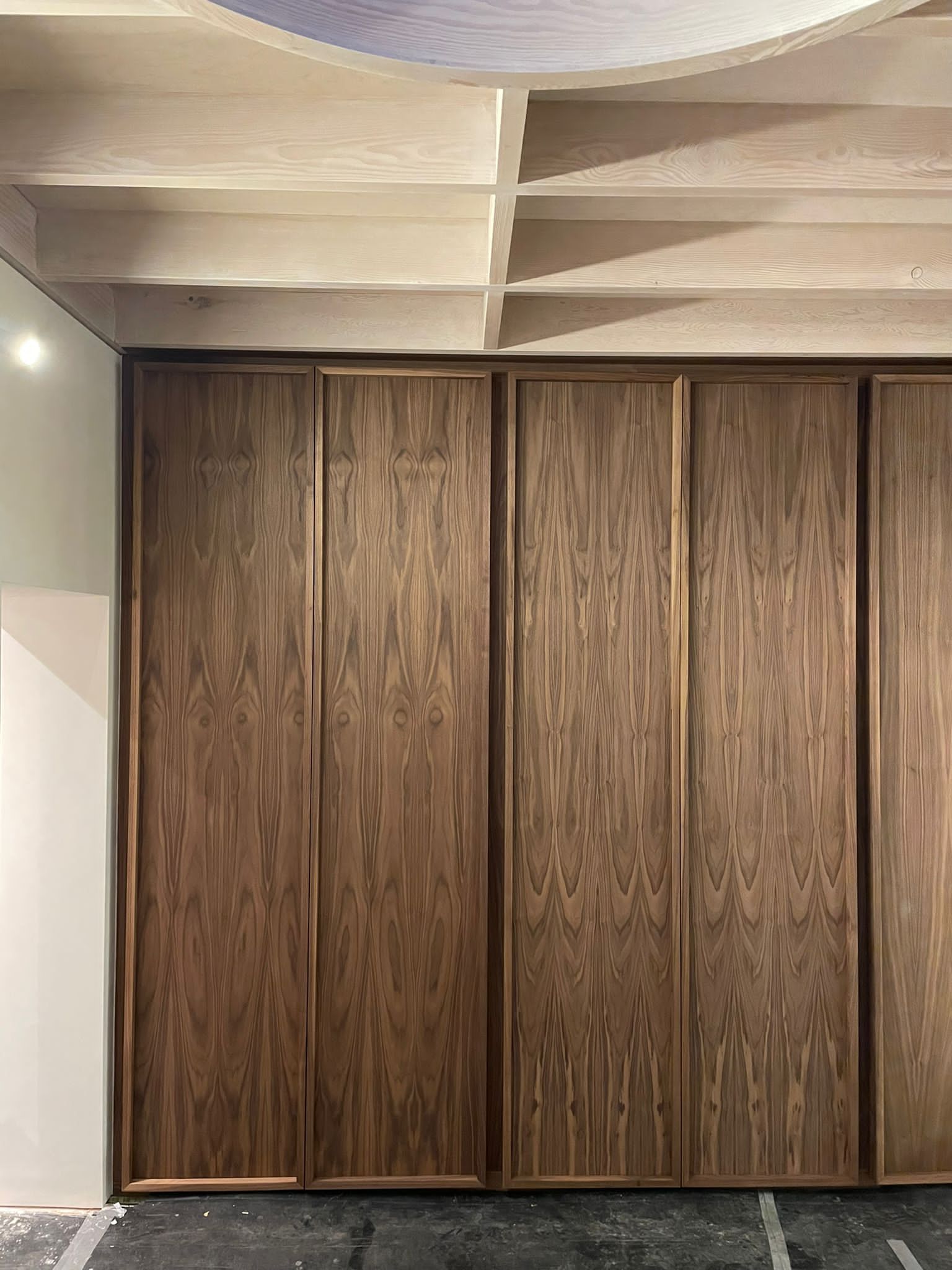 Wooden panel sliding doors on a wall, with a light-colored ceiling.