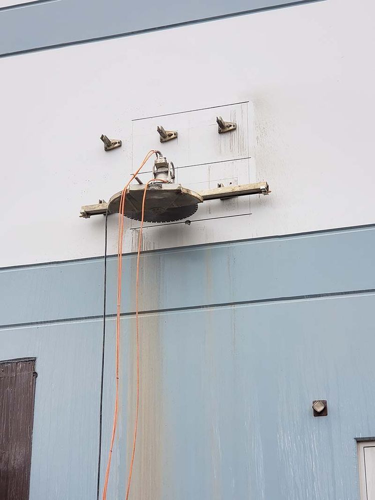 A machine is cutting a hole in the side of a building