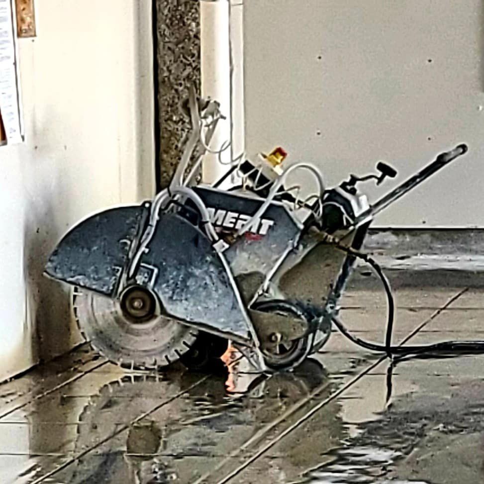 A concrete saw is sitting on the floor next to a door.