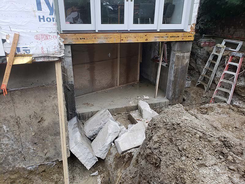 A house under construction with a ladder in the dirt.