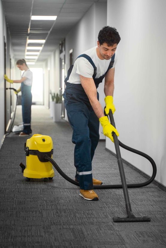 A man cleaning a carpet within a commercial building. 