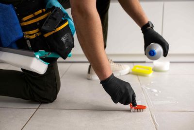 A man scrubbing against tile to get it clean.