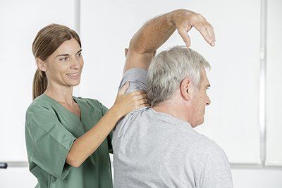 A nurse is helping an older man stretch his arms.