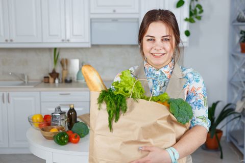 Woman in the kitchen with a bag of groceries