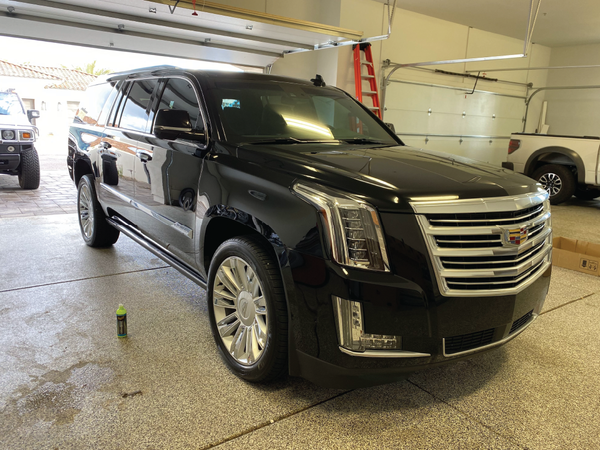 A black cadillac escalade is parked in a garage.