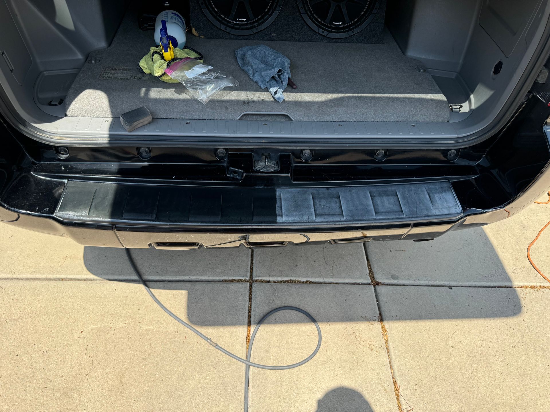 The back bumper of a black suv is being installed.