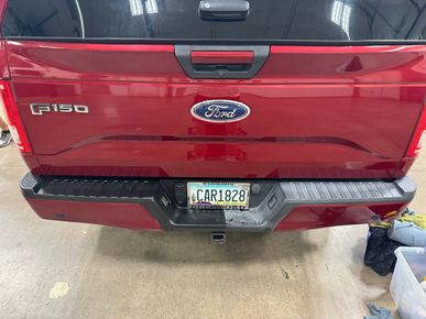 A red ford f150 truck is parked in a garage.