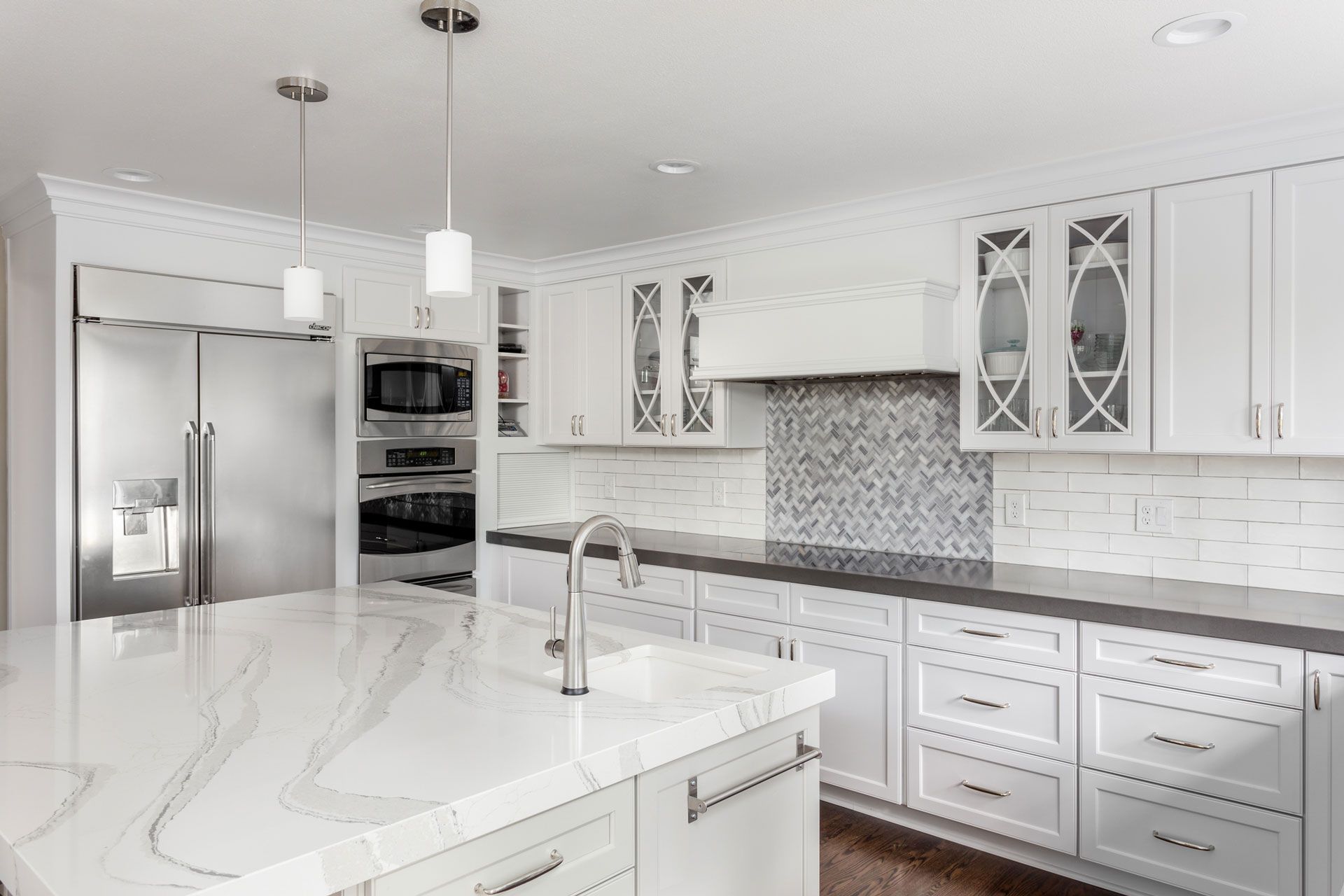 A kitchen with white cabinets, granite counter tops, stainless steel appliances and a large island.