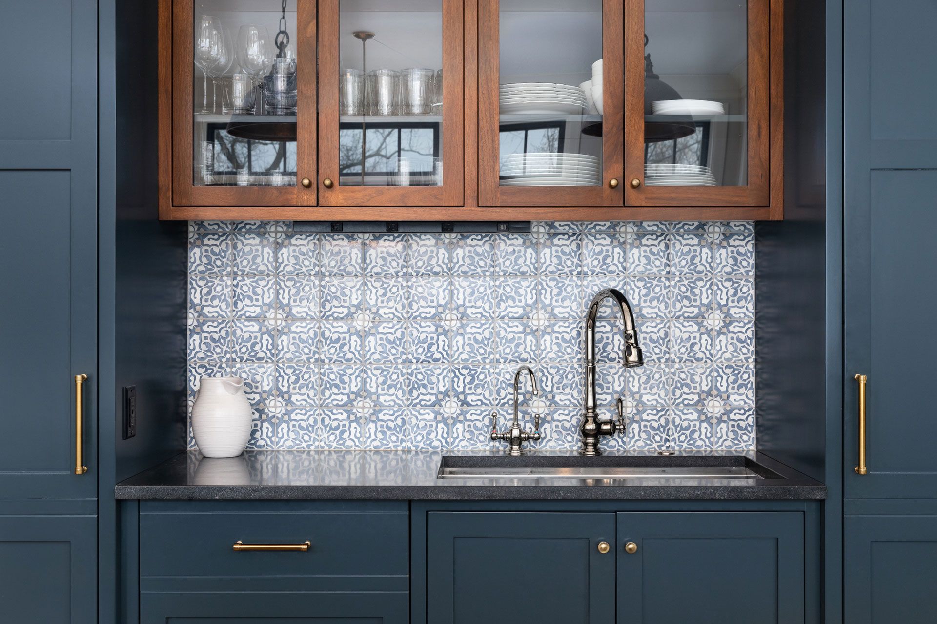 A kitchen with blue cabinets and a sink with a glass door