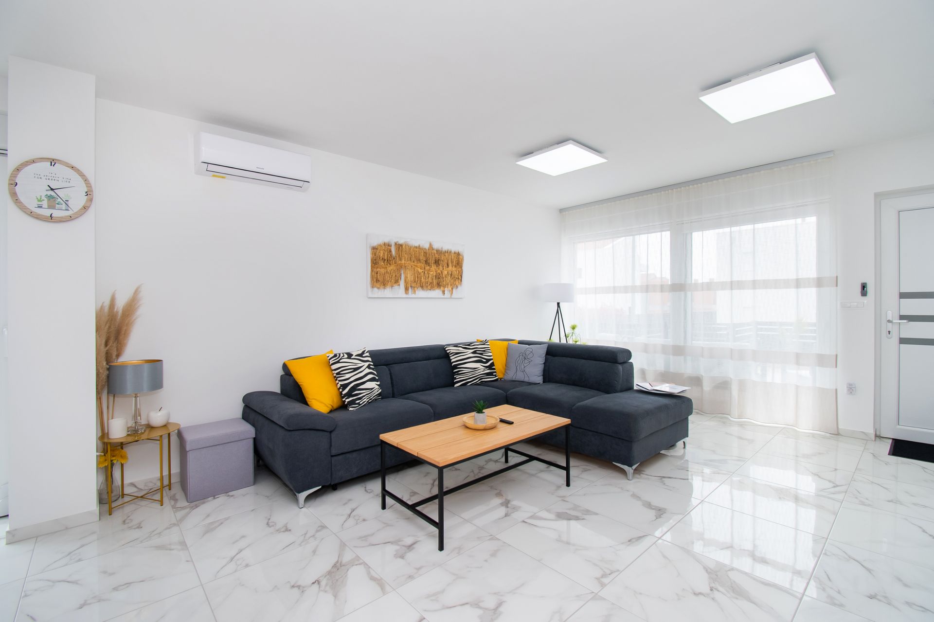 Modern living room with gray sectional sofa, wooden coffee table, and white marble floors.