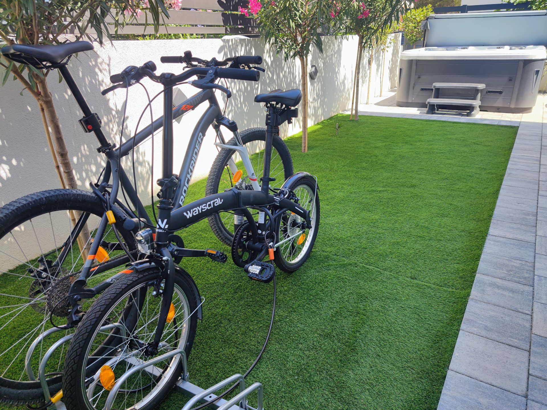 Two bikes parked on artificial grass; hot tub in the background.