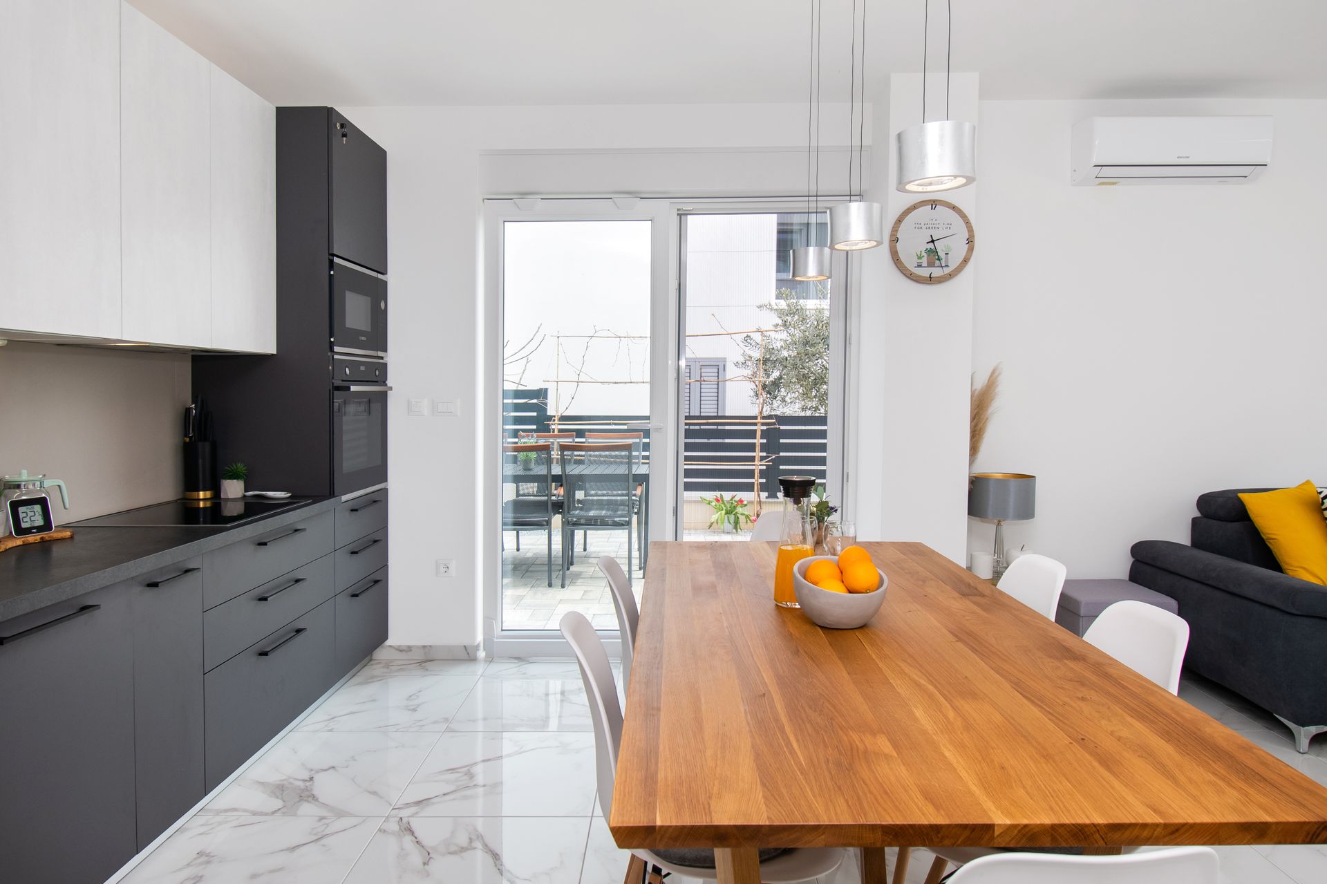 Modern kitchen and dining area with gray cabinets, wooden table, and outdoor access.