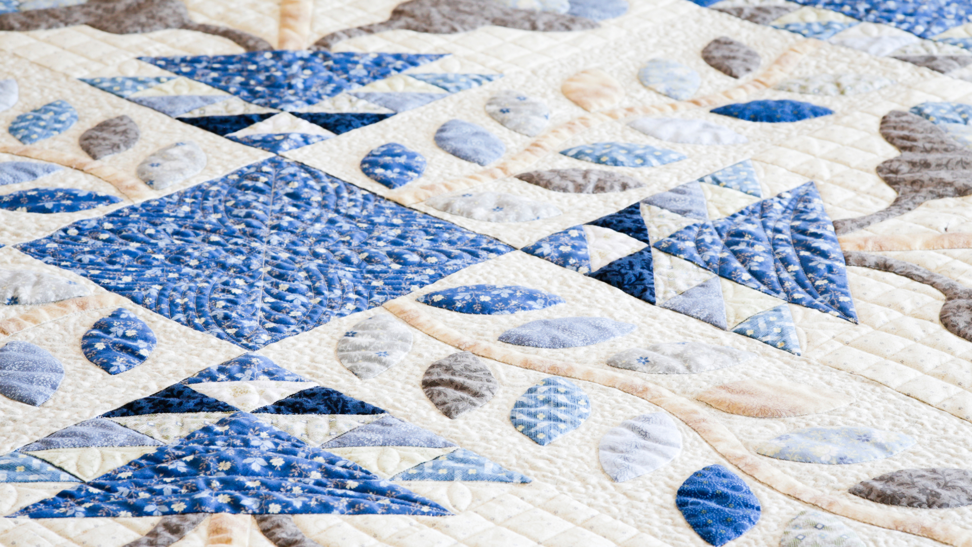 A close up of a blue and white quilt with a geometric pattern.