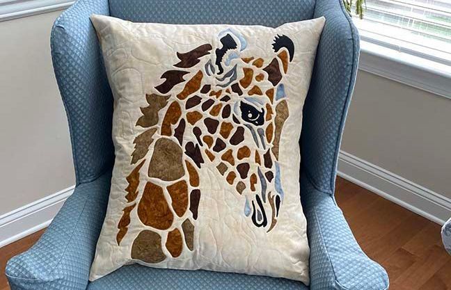 A giraffe pillow is sitting on a blue chair.