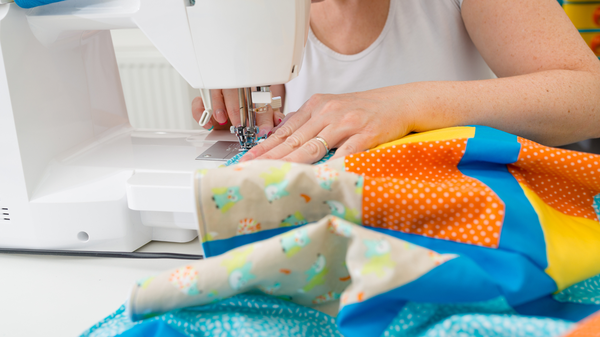 A woman is using a sewing machine to make a quilt.